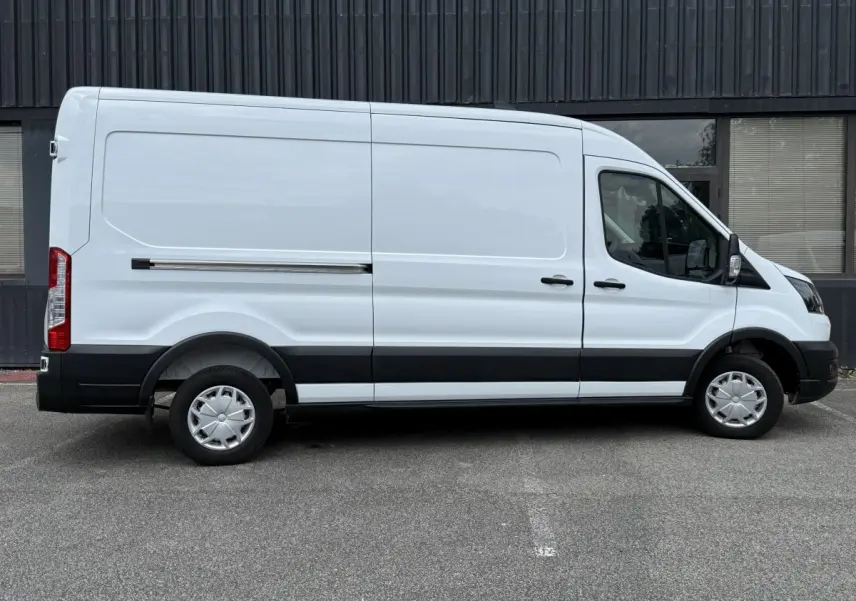 Vue latérale droite d’un fourgon Ford Transit blanc avec bande noire et jantes acier à enjoliveurs.