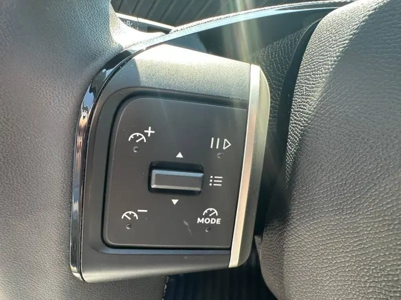 Gros plan sur les commandes du régulateur de vitesse au volant noir de la Citroën C3 2025.