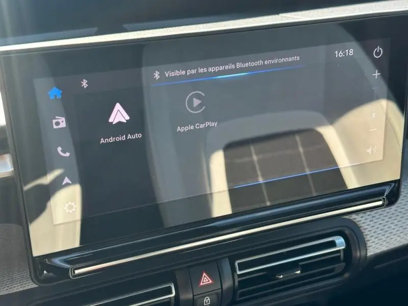 Écran tactile central de la Citroën C3 2025 affichant les options Android Auto et Apple CarPlay, avec reflets lumineux.