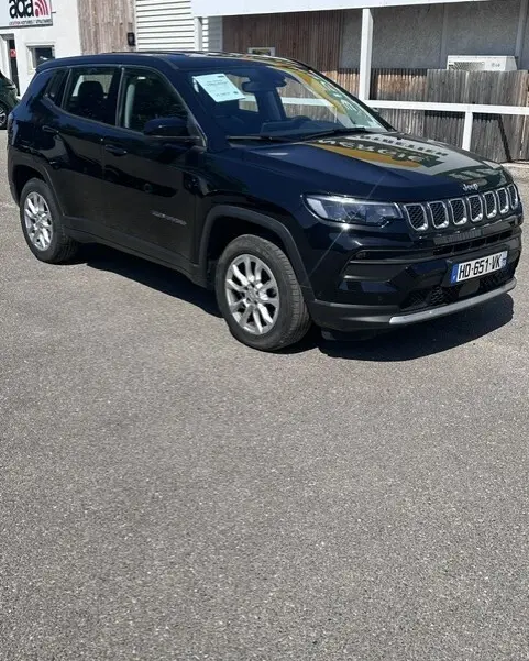 Jeep Compass noir en 3/4 avant droit, avec jantes alliage 18 pouces, stationné sur un parking extérieur.