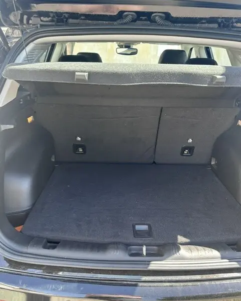 Coffre ouvert vu de l'arrière d'un Jeep Compass noir 2025, montrant un espace de chargement propre avec cache-bagages relevé.