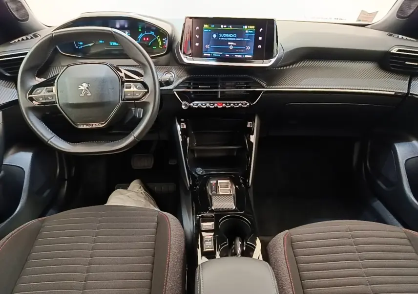 Vue intérieure avant du Peugeot E-2008 électrique, tableau de bord moderne avec écran tactile central et volant multifonctions.