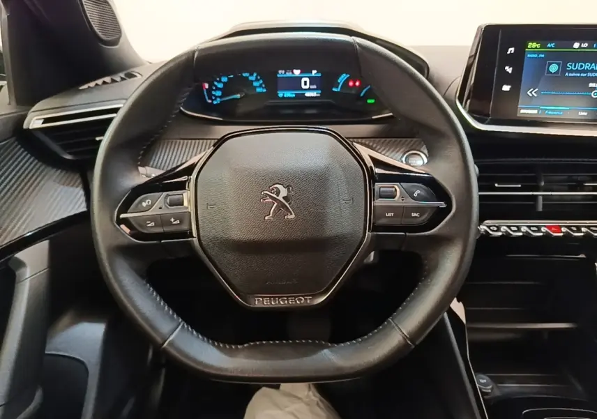 Vue intérieure centrée sur le volant cuir noir du Peugeot E-2008 électrique avec tableau de bord digital et écran tactile.