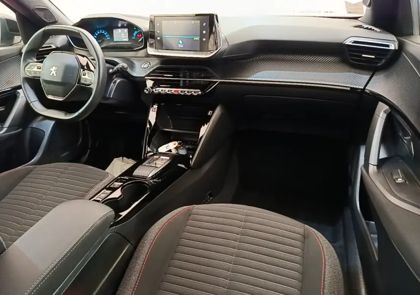 Intérieur du Peugeot E-2008 électrique gris clair, vue avant centrée sur le tableau de bord et le volant multifonctions cuir.