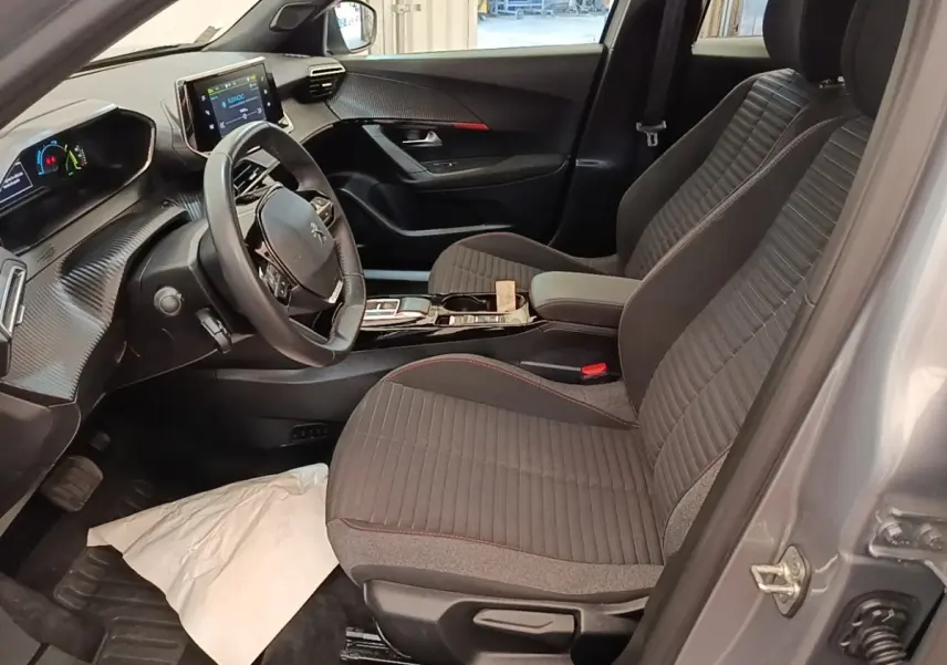 Vue intérieure côté conducteur du Peugeot E-2008 électrique gris clair 2023, avec tableau de bord digital et sièges tissu.