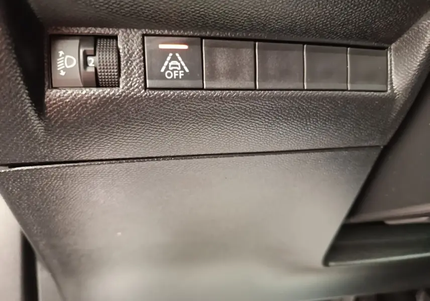 Gros plan sur les commandes noires du tableau de bord côté gauche du Peugeot E-2008 électrique gris clair 2023.