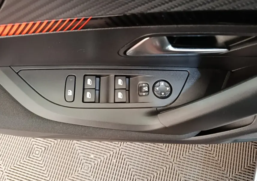 Gros plan sur la commande des vitres et rétroviseurs côté conducteur de la Peugeot E-2008 électrique gris clair, avec poignée de porte.