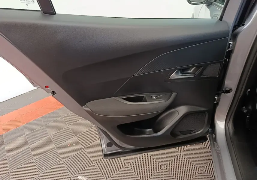 Vue intérieure de la porte arrière droite gris clair du Peugeot E-2008 électrique Active Pack 2023, avec poignée et haut-parleur intégrés.