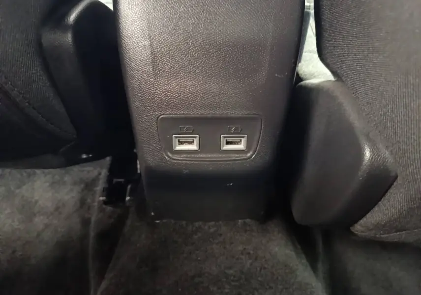 Gros plan sur les ports USB doubles arrière intégrés dans la console centrale noire du Peugeot E-2008 électrique gris clair.