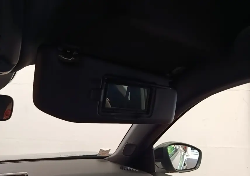 Intérieur côté conducteur du Peugeot E-2008 gris clair 2023, avec pare-soleil et miroir de courtoisie ouvert.