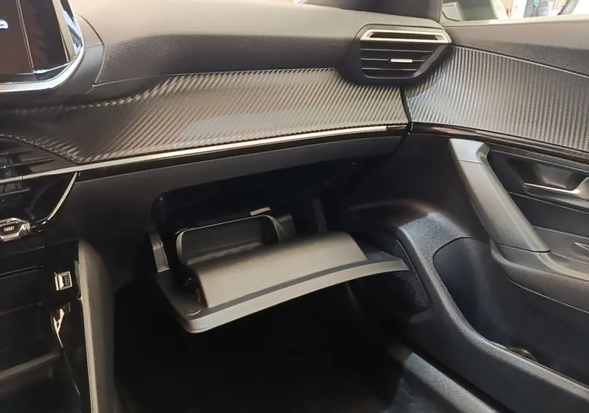 Intérieur côté passager du Peugeot E-2008 gris clair 2023, avec boîte à gants ouverte et tableau de bord texturé.