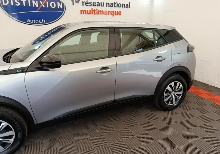 Profil côté gauche du Peugeot E-2008 électrique gris clair 2023 avec jantes et rétroviseurs noirs.