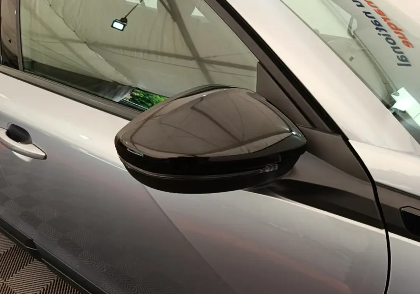 Vue rapprochée du rétroviseur droit noir sur la porte gris clair d’un Peugeot E-2008 électrique 2023.