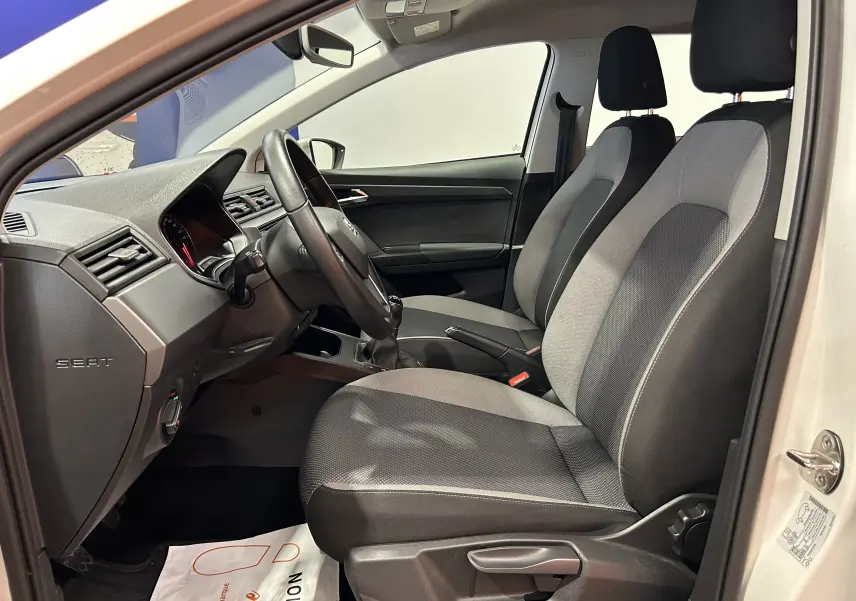 Intérieur avant droit d'une SEAT Ibiza blanche 2019, sièges tissu gris avec volant multifonction et boîte manuelle.