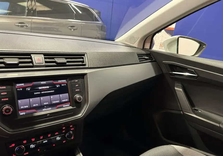 Intérieur côté passager de la SEAT Ibiza blanche 2019, tableau de bord et console centrale avec écran tactile allumé.