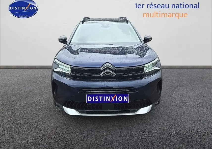 Vue frontale d'un Citroën C5 Aircross bleu eclipse avec phares LED allumés sur sol goudronné.