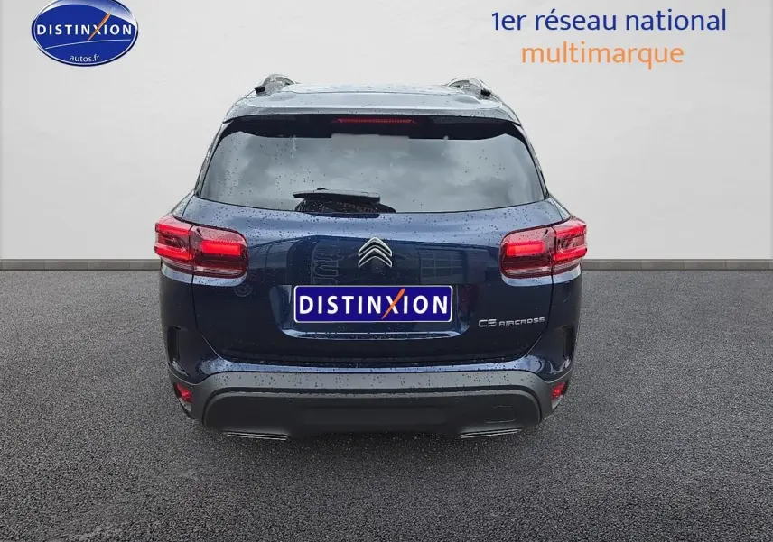 Vue arrière d'un Citroën C5 Aircross bleu eclipse avec toit noir et barres de toit, sous la pluie.