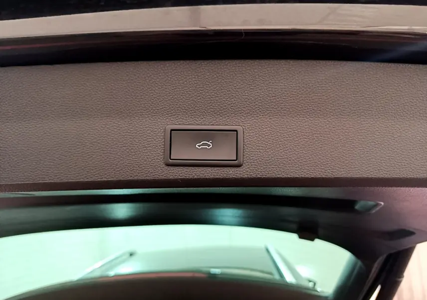 Bouton d'ouverture électrique du coffre sur la partie intérieure du hayon d'un SEAT Ateca noir, vue en contre-plongée.