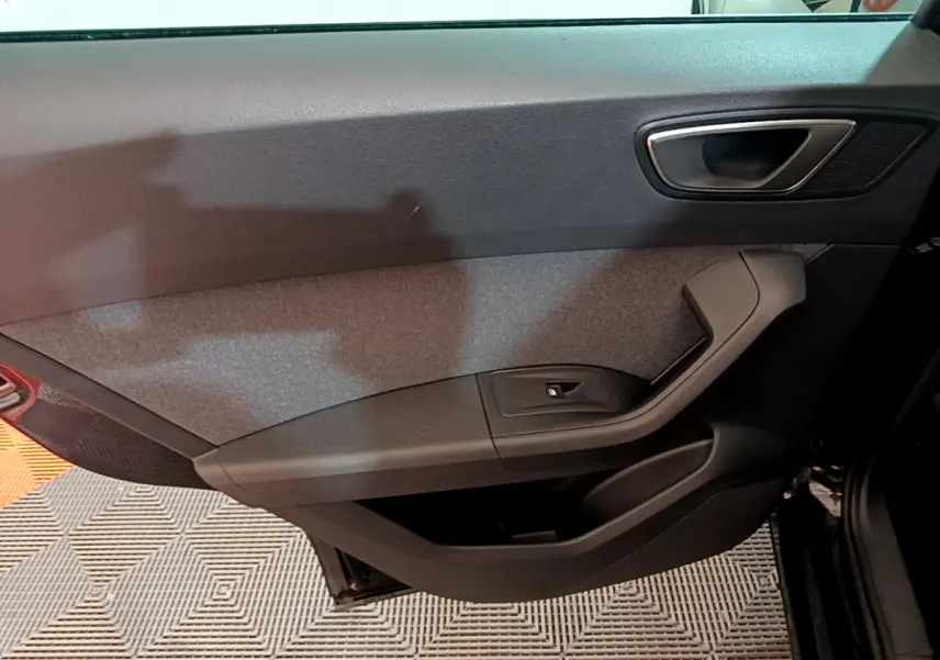 Intérieur côté gauche de la porte avant noire du SEAT Ateca 2022 avec poignée argentée et bouton de vitre électrique.