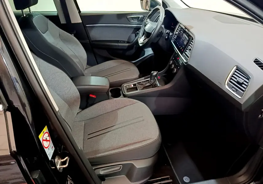 Intérieur avant droit d’un SEAT Ateca noir 2022, sièges gris, tableau de bord moderne avec écran tactile.