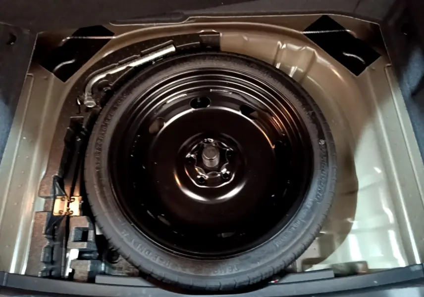 Roue galette de secours noire dans le coffre d'un SEAT Ateca 2022, vue plongeante sur le rangement sous tablette.