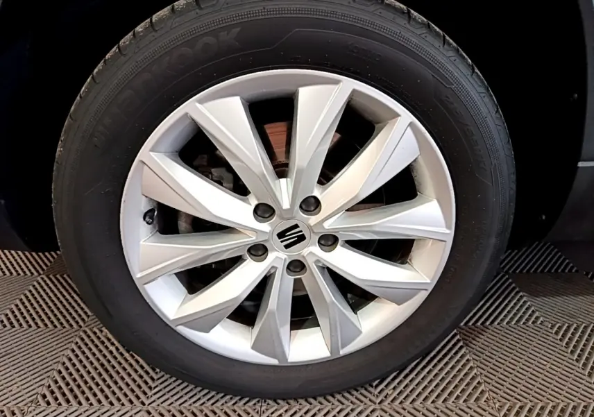 Gros plan sur la roue avant gauche avec jante alliage argentée du SEAT Ateca noir 2022.