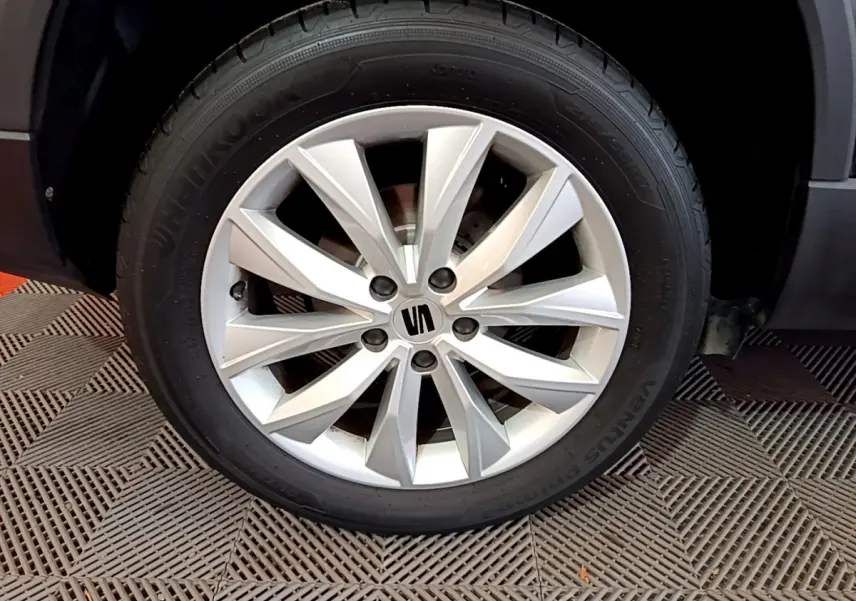 Gros plan sur la roue avant droite du SEAT Ateca noir, mettant en valeur la jante aluminium à dix branches.