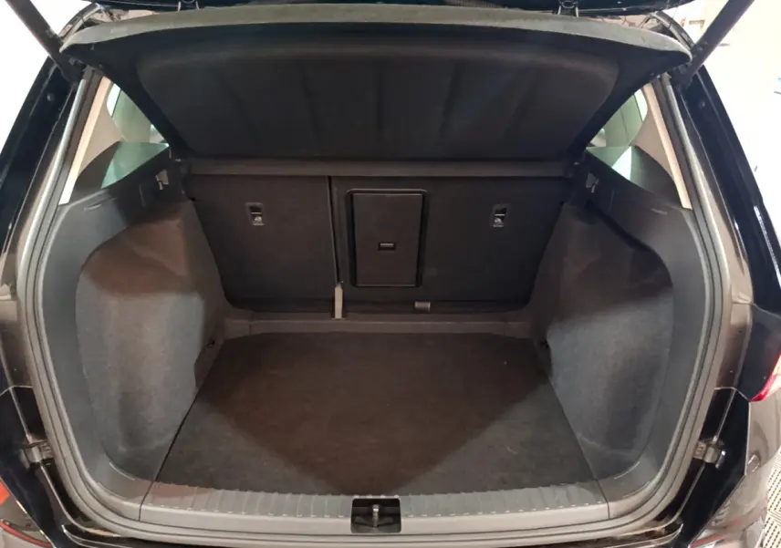 Coffre ouvert vu de l'arrière d'un SEAT Ateca noir 2022, espace de chargement spacieux et habillage sombre.