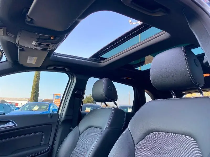 Vue intérieure avant de la Mercedes Classe B 180 d 2016, sièges noirs et toit ouvrant panoramique ouvert.