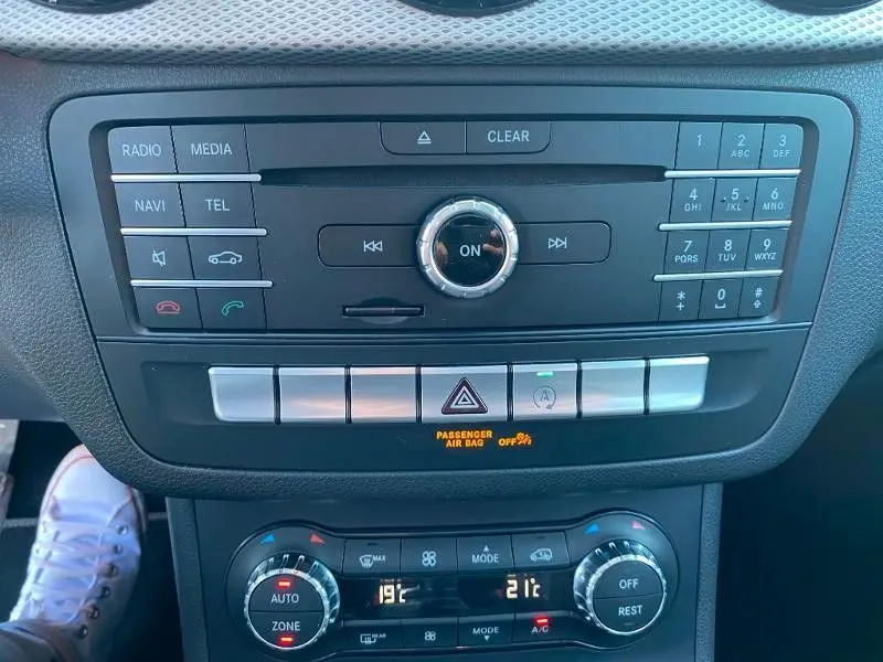 Vue rapprochée de la console centrale de la Mercedes Classe B 180 d 2016, avec commandes multimédia et climatisation.