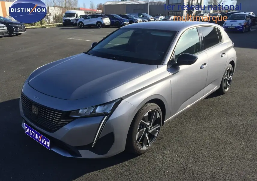 Vue 3/4 avant droit d'une Peugeot 308 gris Artense métal 2025 avec calandre noire et jantes bi-ton.