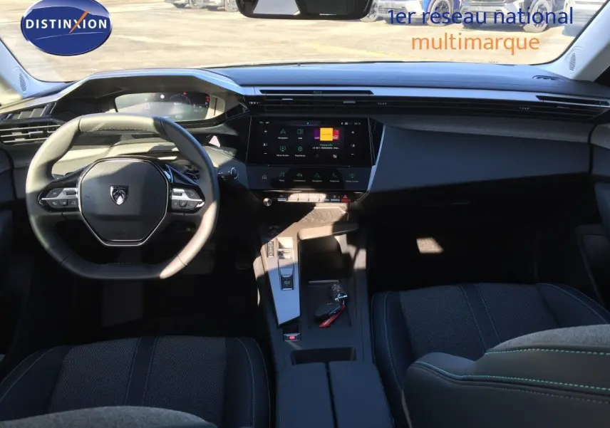 Intérieur de la Peugeot 308 2025, vue de face sur le tableau de bord et volant, ambiance sombre avec finitions noires.