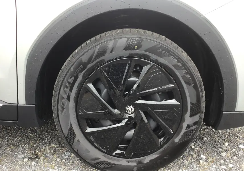 Gros plan sur la roue avant droite du MG ZS Cosmic Silver avec jante noire à motifs aérodynamiques.