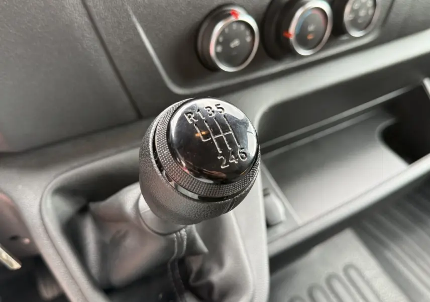 Gros plan sur le levier de vitesses manuel noir du Renault Master 2024, avec commandes de climatisation en arrière-plan.