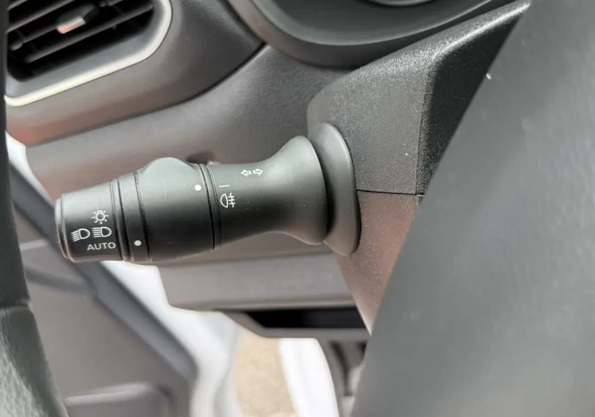 Gros plan sur la manette de commande des phares et clignotants du tableau de bord intérieur du Renault Master blanc.