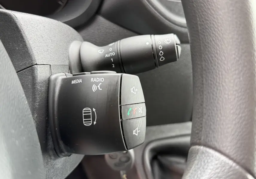 Gros plan sur commande multimédia et essuie-glace derrière volant noir du Renault Master 2024, intérieur sombre.