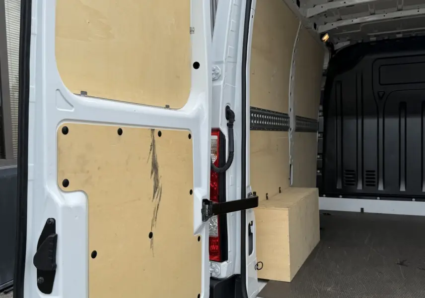 Vue intérieure arrière droite du Renault Master blanc 2024 avec cloison et aménagements en bois clair.