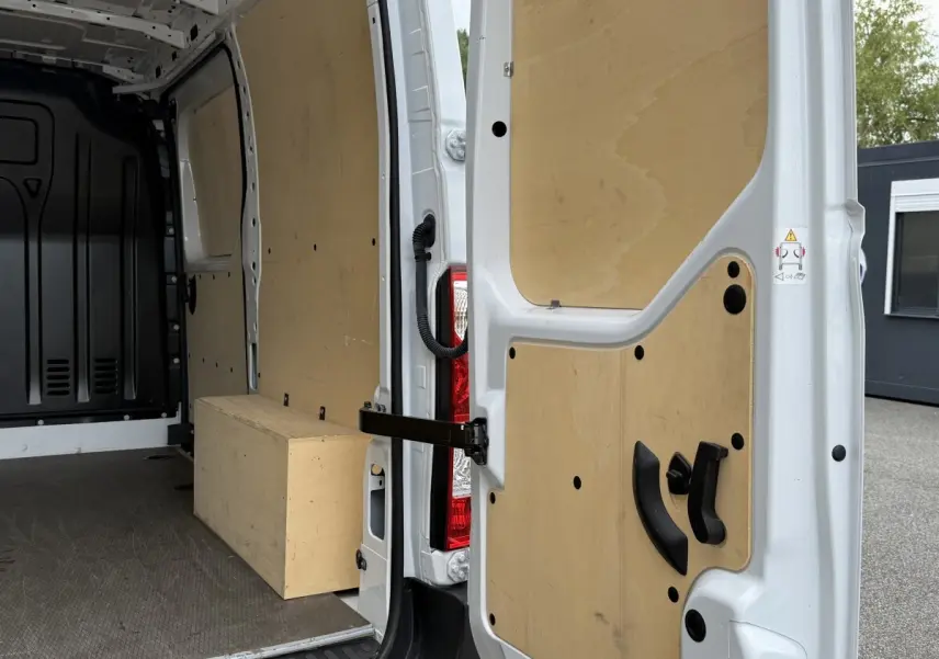 Vue intérieure arrière du Renault Master blanc 2024, montrant la cloison et les portes arrière ouvertes avec habillage bois.