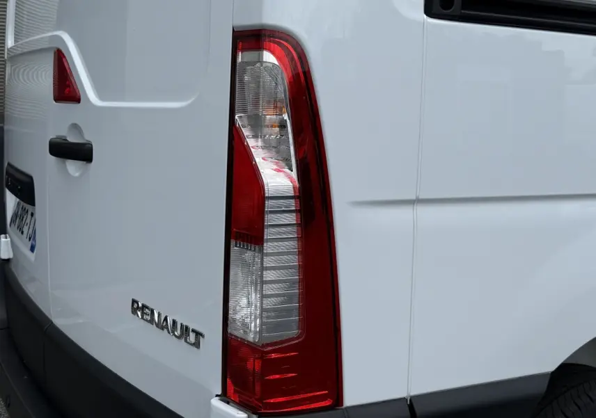 Vue arrière droite d’un Renault Master blanc, mettant en valeur le feu arrière vertical et le logo Renault sur la porte.