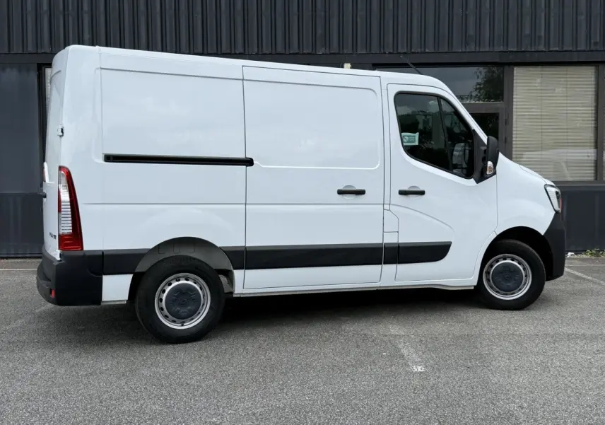 Vue de profil côté droit du Renault Master blanc avec jantes acier et bandeau noir sur porte latérale.