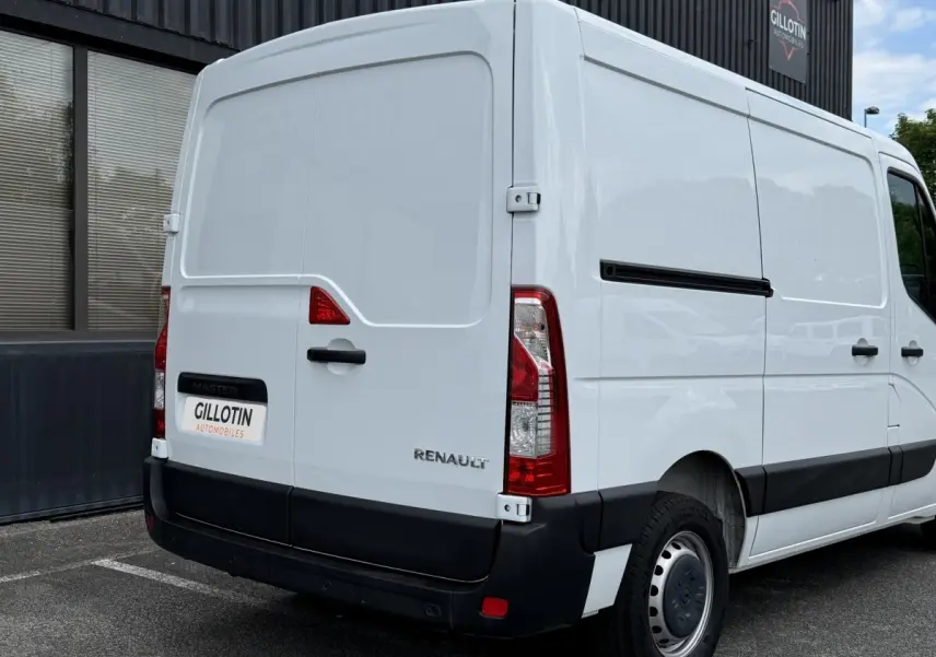 Vue 3/4 arrière droite d’un utilitaire Renault Master blanc avec porte latérale coulissante et feux arrière verticaux.