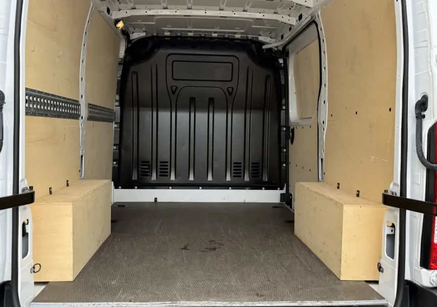Vue intérieure arrière du Renault Master blanc 2024, montrant l'espace de chargement avec parois en bois et cloison noire.