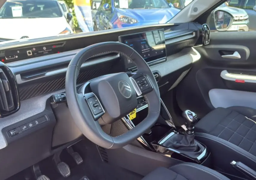 Intérieur de la Citroën C3 2025 vu côté conducteur, volant multifonctions et boîte manuelle en évidence.