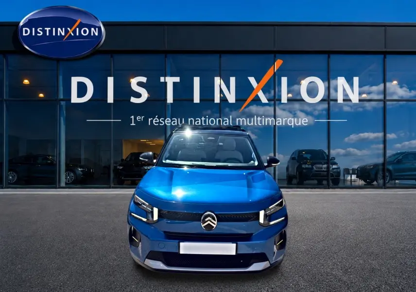 Citroën C3 bleu vue de face, avec calandre distinctive et phares LED, devant une vitrine Distinxion.