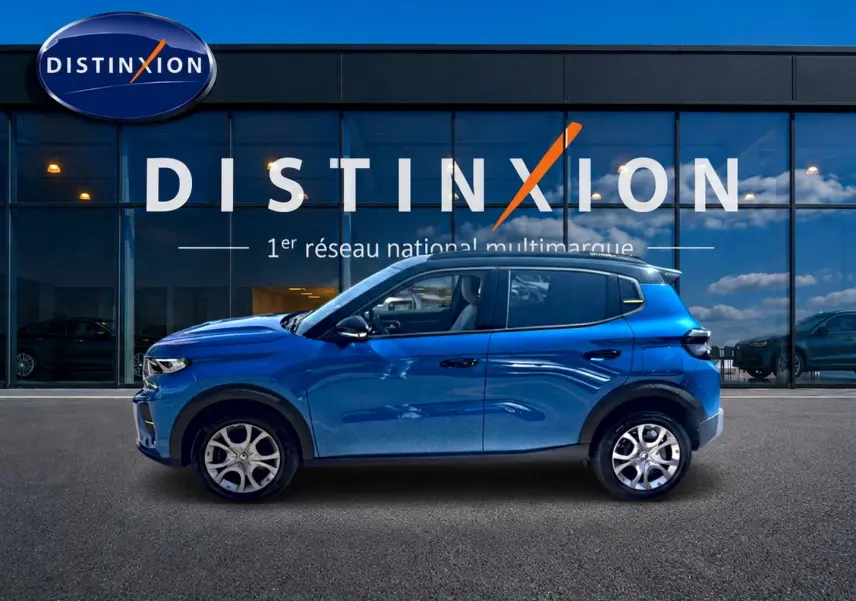 Profil latéral droit d'une Citroën C3 2025 bleu, avec jantes alu et toit noir devant une vitrine Distinxion.