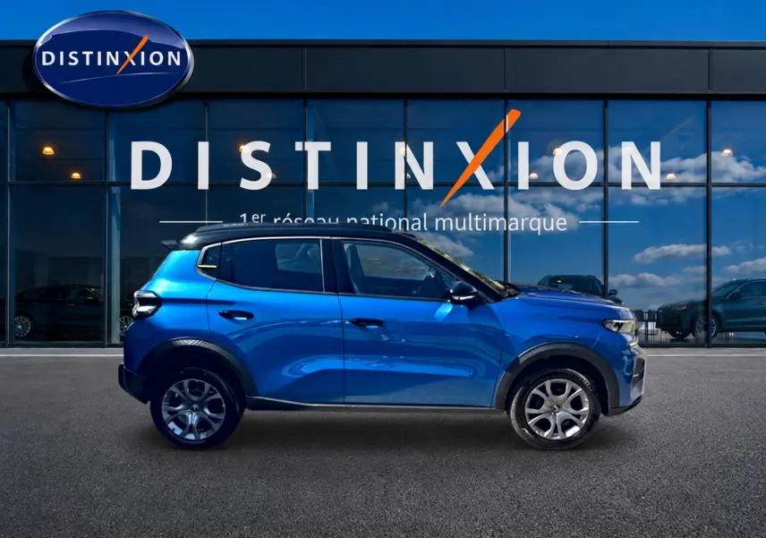 Profil droit d'une Citroën C3 bleu 2025 avec jantes alu, garée devant une vitrine Distinxion.