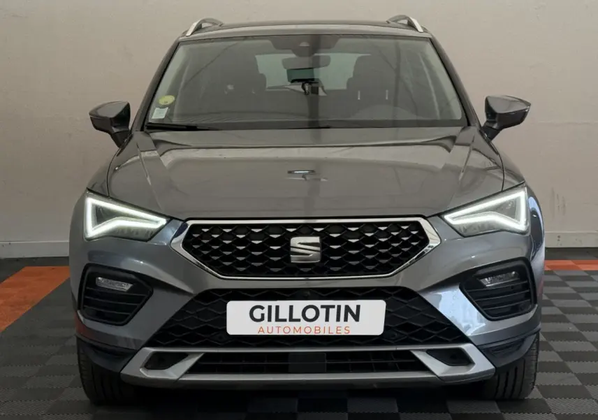 Vue frontale d'un SEAT Ateca gris clair 2023 avec phares LED allumés et calandre noire distinctive.