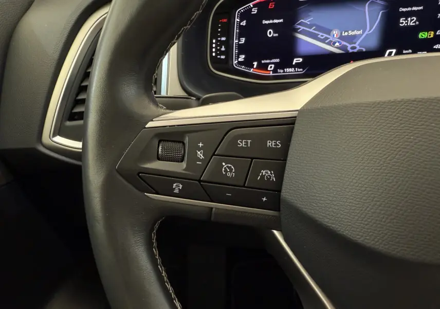 Gros plan sur le volant cuir noir du SEAT Ateca 2023 avec commandes de régulateur et tableau de bord numérique.