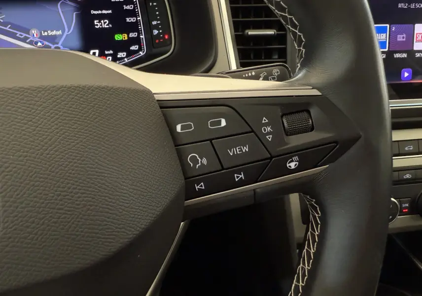 Gros plan sur les commandes du volant en cuir noir avec surpiqûres blanches du SEAT Ateca gris clair 2023.