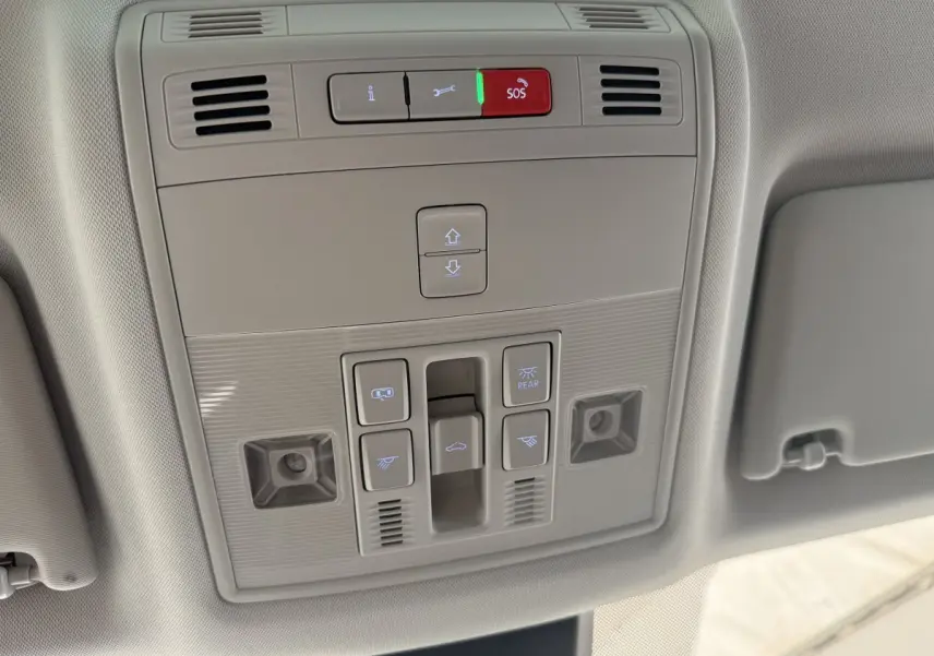 Vue en contre-plongée du panneau de commandes au plafond du SEAT Ateca gris clair 2023 avec bouton SOS illuminé rouge.
